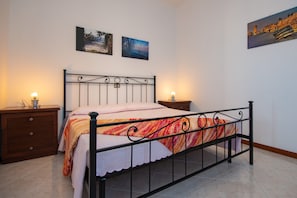 A bedroom with a metal bed frame, a wooden nightstand, a bedside table, and two wall-mounted lamps.