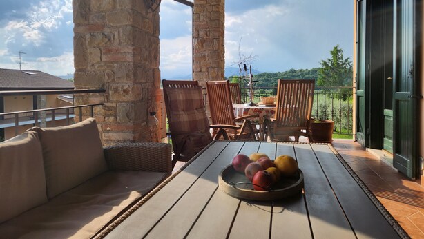 Una terraza de madera con una mesa, sillas y un frutero.