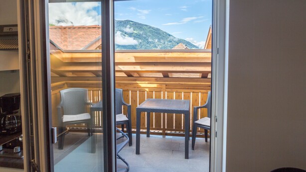 Un balcon avec une table et des chaises, une clôture en bois et une vue sur la montagne.