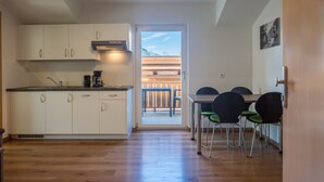 Une cuisine moderne avec des meubles blancs, une machine à café et un coin repas comprenant une table et des chaises.