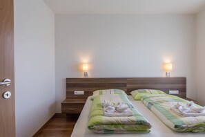 A hotel room with two beds, wooden headboards, bedside lamps, and a wooden floor.