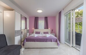 A bedroom with a bed, a nightstand, a chair, a wardrobe, and a sliding glass door to an outdoor area. - Villa Green Palm at the Sea with Large Terrace (Vrsar)
