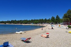 A beach with sun loungers, umbrellas, and boats. - Villa Green Palm at the Sea with Large Terrace (Vrsar)
