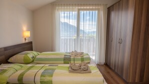 Een hotelkamer met twee bedden, een houten garderobe, een nachtkastje met een lamp en een raam met gordijnen.