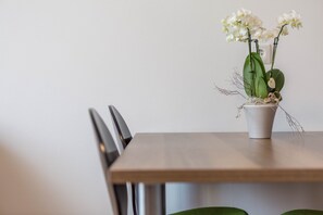 A dining table with chairs, a potted orchid, and a wall socket.