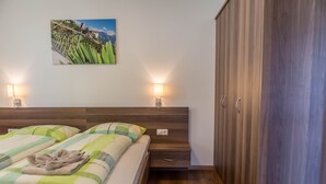 Une chambre à coucher avec un lit, deux lampes de chevet, une armoire en bois et un tableau accroché au mur.