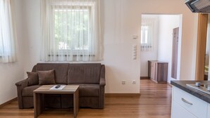 Un salon moderne avec un canapé, une table basse et un coin cuisine à l’arrière-plan.