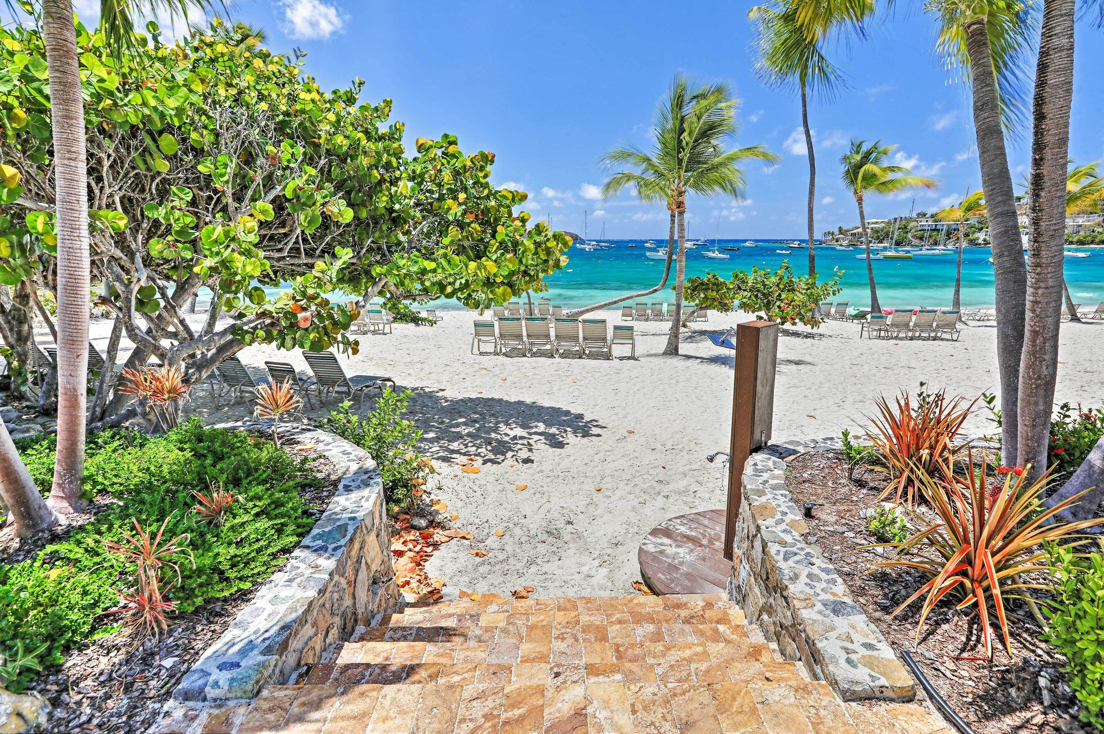 A beach with a stone staircase leading to a lounge area with chairs and a view of the ocean.