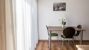Ein Essbereich mit einem Holztisch, zwei Stühlen, einer Zimmerpflanze und einem Schwarz-Weiß-Foto an der Wand.