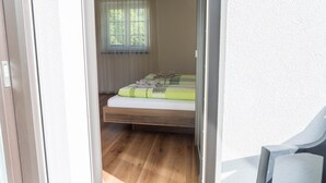 Ein Schlafzimmer mit einem Bett, einem Fenster mit Vorhängen und einem Holzboden.