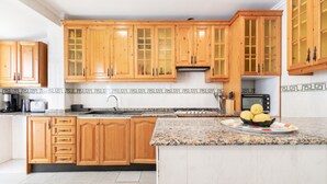A kitchen with wooden cabinets, a granite countertop, and a microwave.