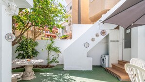 A courtyard with a table, chairs, a washing machine, and steps leading to an upper level.