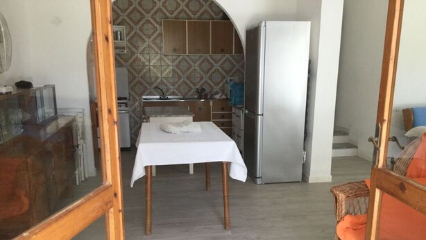 Una habitación con mesa de comedor, kitchenette y refrigerador.