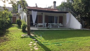 Una casa con porche cubierto, camino de piedra y césped.