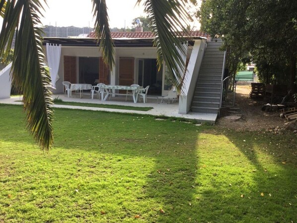 A modern building with a covered patio area, outdoor seating, and a well-maintained lawn.