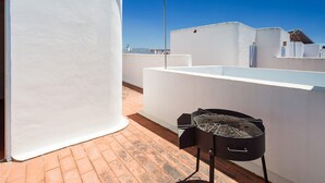 A rooftop terrace with a barbecue grill, white walls, and a clear blue sky. - Spacious Holiday Apartment "Duplex A Fontanilla" Near the Beach (Conil de la Frontera)