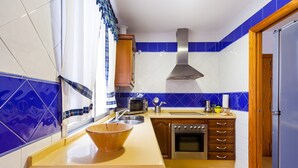 A kitchen with a wooden countertop, stainless steel appliances, and blue and white tiles. - Spacious Holiday Apartment "Duplex A Fontanilla" Near the Beach (Conil de la Frontera)
