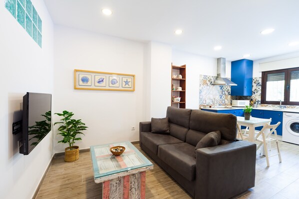Un salon avec un canapé, un téléviseur, une table basse et une plante.