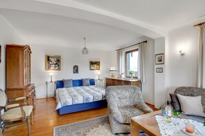 A bedroom with a bed, a chair, a table with drinks, and a window. - Apartment 1 with Mountain View, Wi-Fi & Balcony (Grassau)