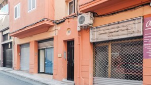 Un bâtiment avec des volets fermés, un climatiseur visible et un portail en métal.