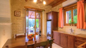 Una cucina rustica con un tavolo di legno, pareti in pietra e una finestra con tende.