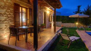 Patio esterno con pareti in pietra, una pergola in legno e zona piscina.