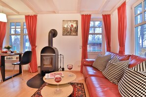 Ein gemütliches Wohnzimmer mit Kamin, einer Ledersofa und einem Essbereich mit Tisch und Stühlen.