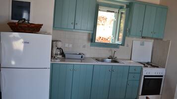A kitchen with teal cabinets, a white refrigerator, a stove, and a sink.