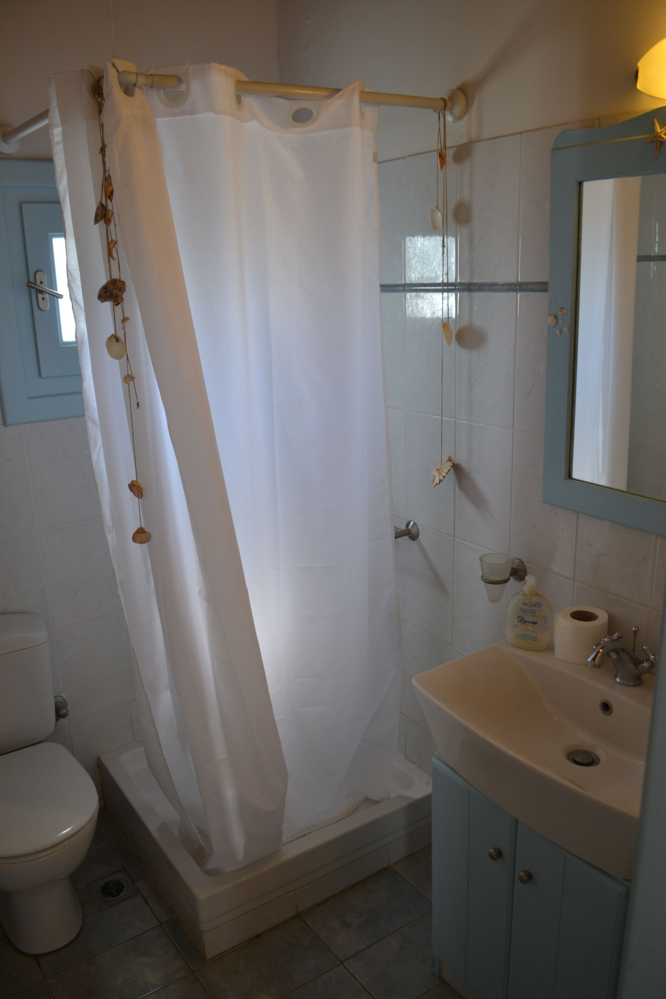 A bathroom with a shower curtain, a toilet, a sink, and a mirror.