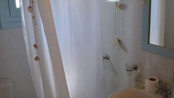 A bathroom with a shower curtain, a toilet, a sink, and a mirror.