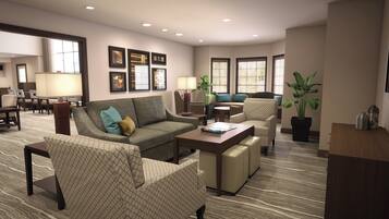 A hotel living room with a sofa, armchairs, a coffee table, and a dining area in the background.