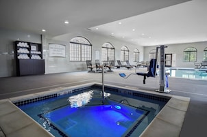Una piscina con un letrero de salvavidas, sillas de descanso y una zona de sauna.