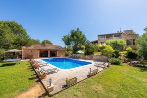 Un jardin avec une piscine, des chaises longues et un espace patio.