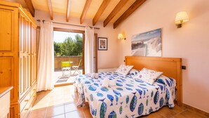 Een slaapkamer met een houten plafond, een bed met een geborduurd beddegoed, een balkon met een stoel en een schilderij aan de muur.