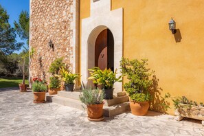 A building with a stone facade, an arched entrance, and potted plants in front.