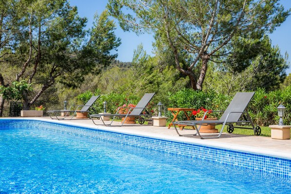 A swimming pool with lounge chairs and potted plants.
