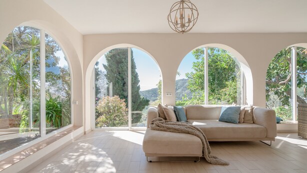 A spacious room with a large window, a sofa, and a chandelier.