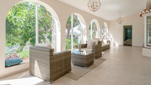A spacious room with large arched windows, wicker furniture, and a hanging light fixture.