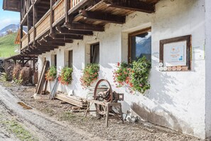 A rustic building with wooden balconies, a window with a sign, and flower boxes on the wall.