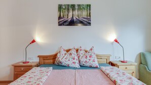 Ein Schlafzimmer mit einem Bett, zwei Nachttischen, einem Beistelltisch, einem Sessel und einem Bild an der Wand.