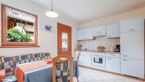 Eine kleine Küche mit weißen Schränken, einer gefliesten Spritzschutzwand und einem Essbereich mit Tisch und Stühlen.