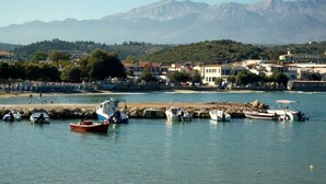 Une ville côtière avec des bateaux amarrés, des bâtiments et des montagnes en arrière-plan.