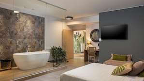 Une salle de bain moderne avec une baignoire sur pieds, un miroir et un téléviseur fixé au mur.