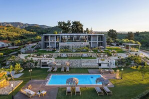 A modern resort with a swimming pool, outdoor seating, and a view of the mountains. - Olivenest Chania Executive Villa (Chania)