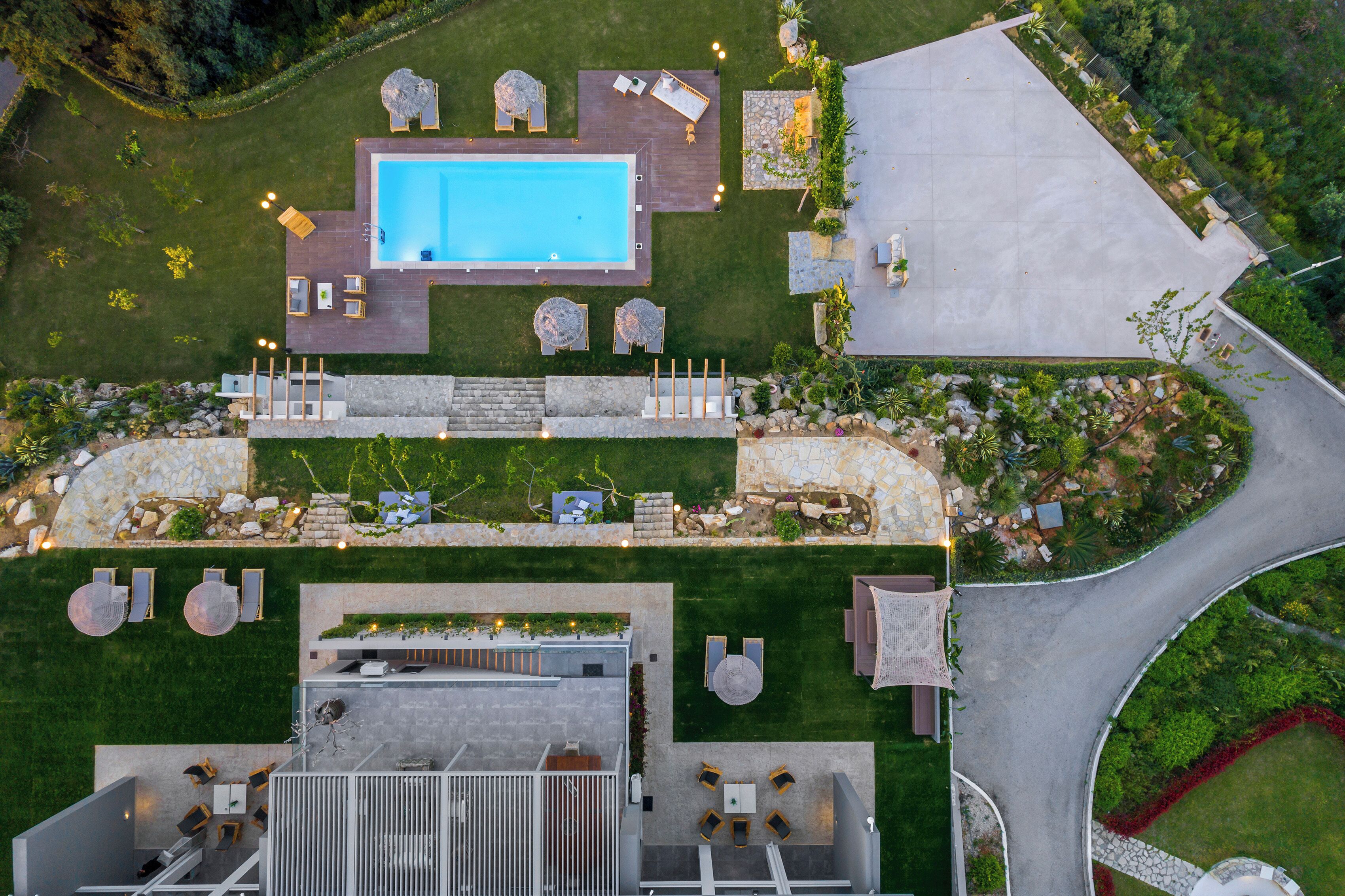 An aerial view of a modern outdoor pool area with multiple seating areas and a stone pathway.