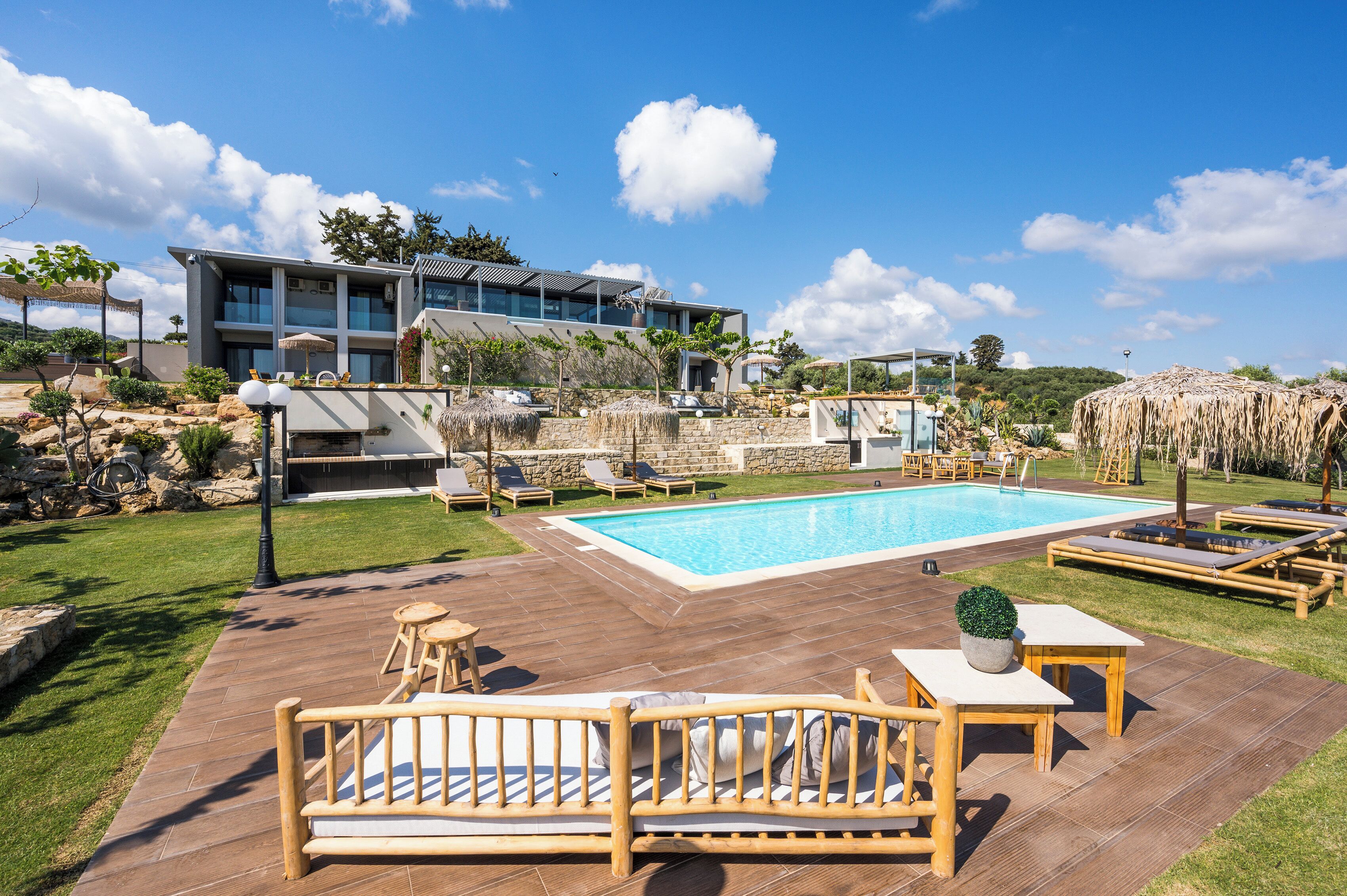 A poolside area with lounge chairs, a wooden deck, and a modern building in the background.