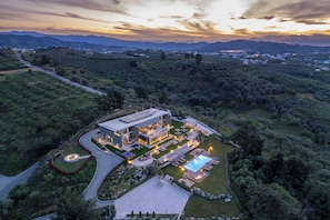 Une maison moderne avec une piscine, entourée d’une végétation luxuriante et avec des montagnes en toile de fond.