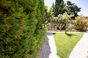Stroll through the beautifully manicured garden, lined with interlocking bricks and lush greenery, to the entrance of this serene property.