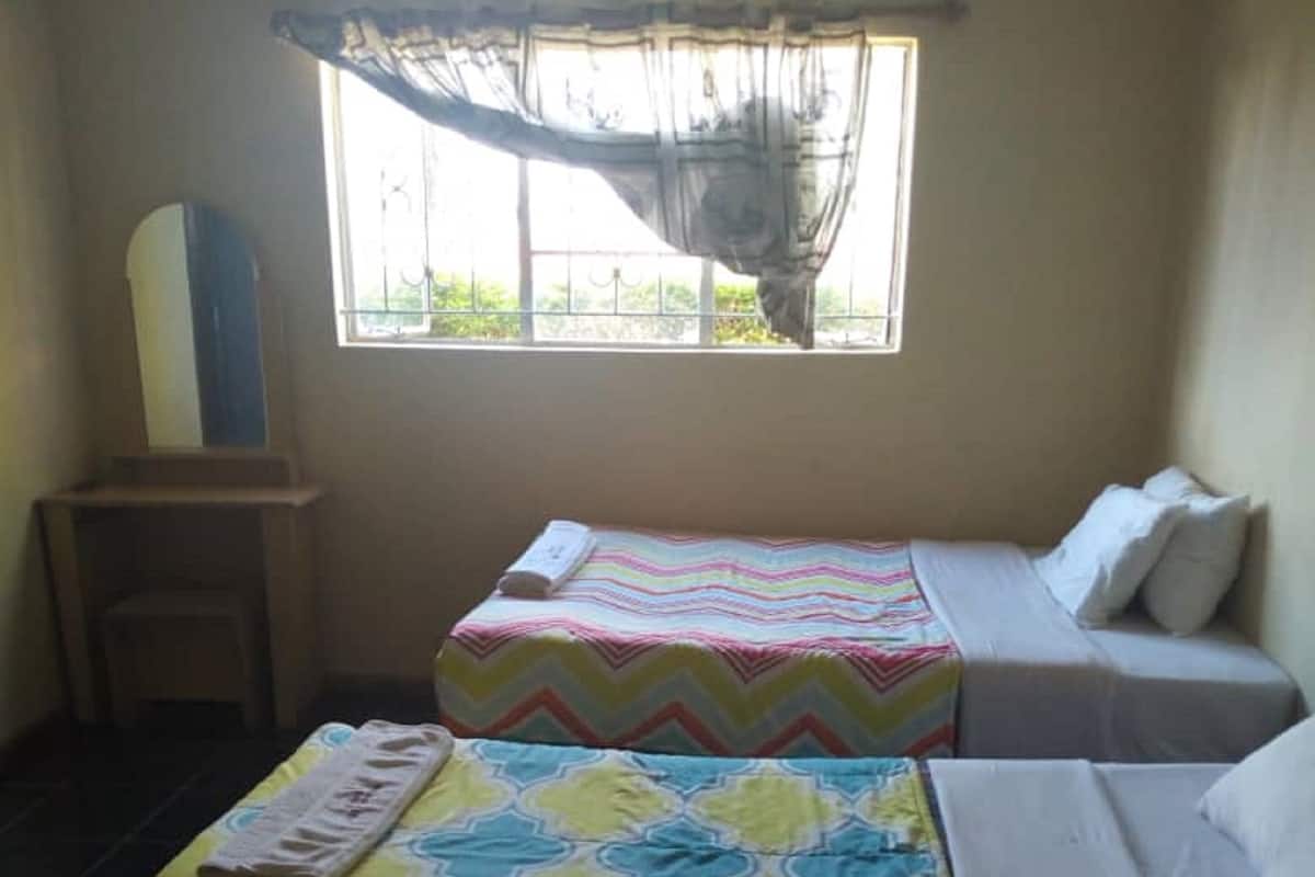 A room with two beds, a window with a view, a mirror, and a small table.