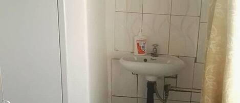 A small bathroom with a white sink, a toilet, and a trash can.